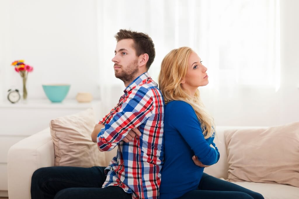 Couple sitting back to back looking fed up