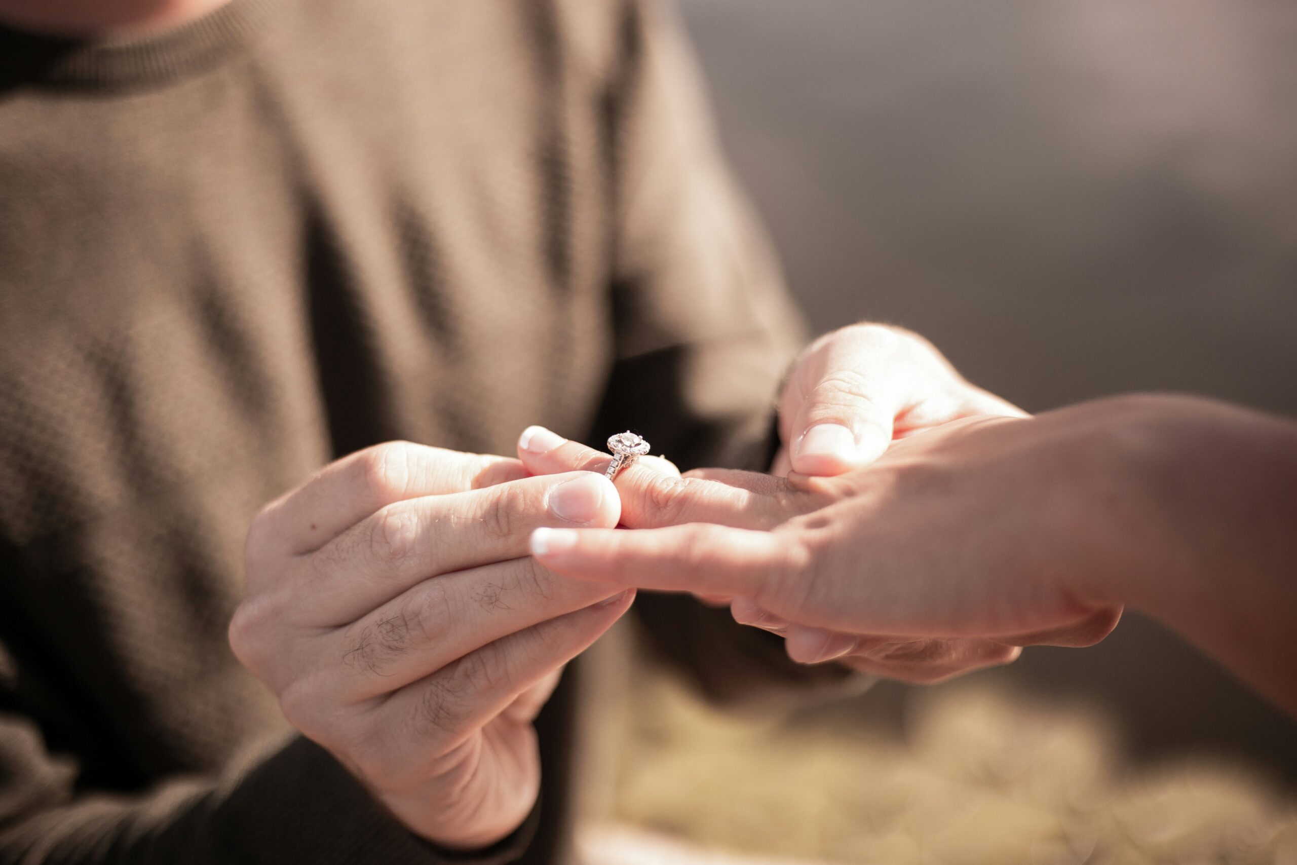 hands putting an engagement ring on another person's finger