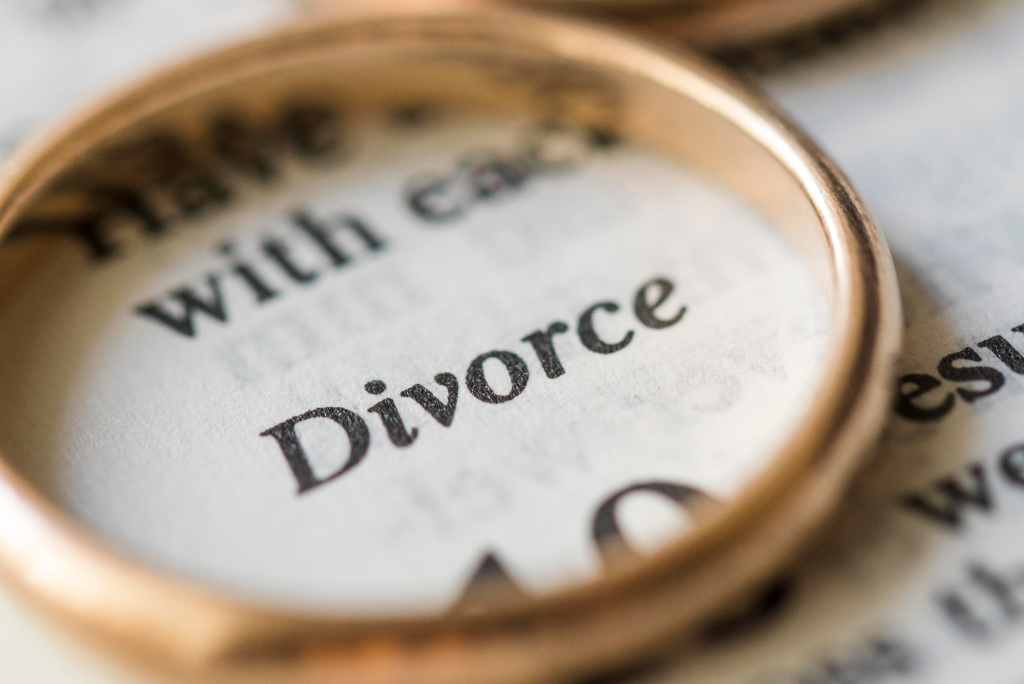 Close-up image of a gold ring placed over a printed page, magnifying the word “Divorce.”